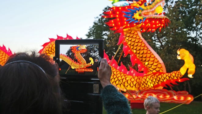 A woman photographs the star of the show, a 200-foot-long dragon, at the China Lights display at Boerner Botanical Gardens.